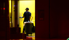 Janitor walking into elevtor with trash bin