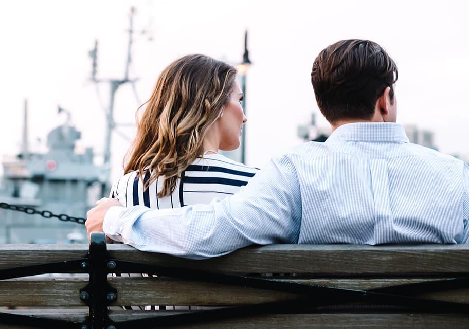 Young couple on bench watching ships sail